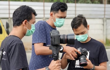 Professional photographers wearing masks review photos on Canon DSLR cameras during an outdoor shoot.