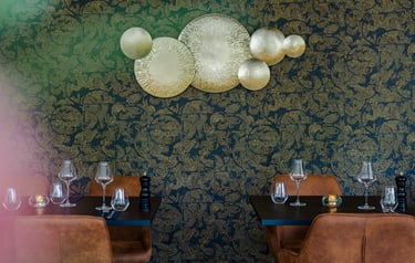 Elegantes Fine-Dining-Restaurant-Interieur mit goldener Wandkunst und braunen Lederstühlen