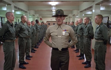 a man in uniform uniform standing in a room with other uniformed personnel
