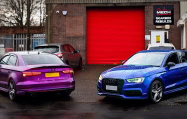 Purple and blue Audi performance cars parked outside a specialized gearbox rebuild garage.