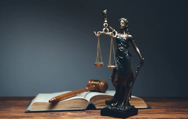 Foto de uma estátua da deusa themis ao lado de um martelo de juiz