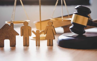 Uma escultura de família ao lado de um martelo de juiz que representam o direito de família