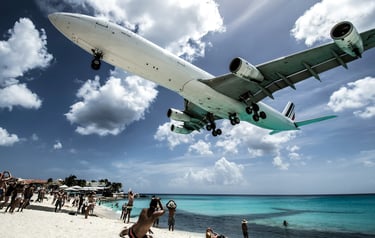 An airplane descending to land over a sandy beach