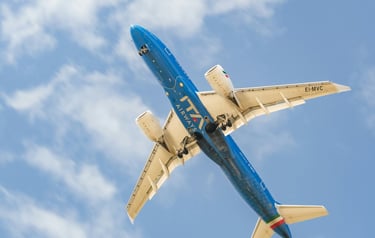 An ITA Airways airplane flying overhead against a clear sky