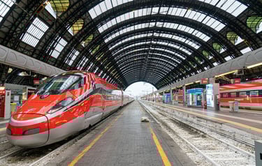 A Trenitalia passenger train standing at a railway station platform