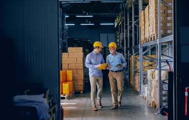 Two Men Wearing Hardhats in Warehouse