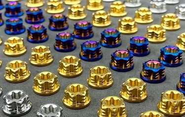 Collection of precision titanium fasteners in various grades and finishes including gold, blue, and 