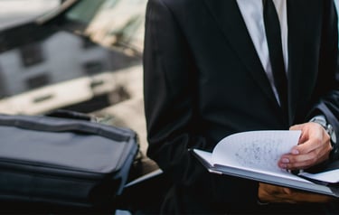 Un professionnel assis sur le capot d’une voiture, en train de prendre des notes sur un carnet.