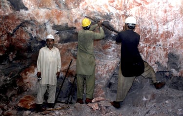 Workers extracting large pink salt blocks at a mining site, preparing them for processing