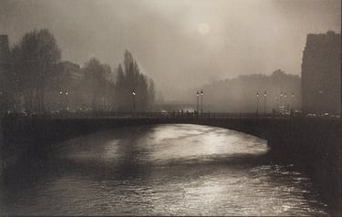 Platinum and silver photography of a foggy bridge over a river in Paris with soft city lights.