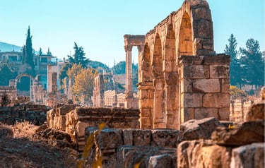 Ancient stone arches and columns at the archaeological ruins of Anjar, Lebanon under a clear blue sky.