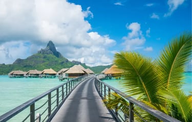 Luxury overwater bungalows in Bora Bora with a walkway leading toward Mount Otemanu and turquoise water.
