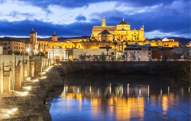 The Roman Bridge and illuminated Mosque-Cathedral of Cordoba at night over the Guadalquivir River.
