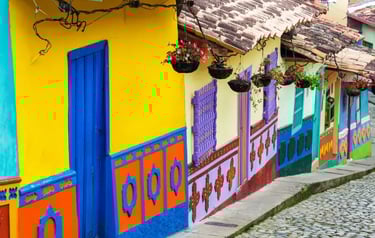 Brightly colored colonial houses with flower baskets on a cobblestone street in Guatape, Colombia.