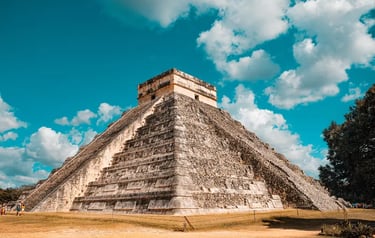 The El Castillo pyramid at Chichen Itza, a famous Mayan archaeological site in Mexico under a blue sky.