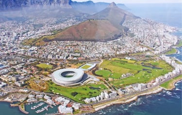 Aerial view of Cape Town Stadium and Table Mountain overlooking the coastal city landscape.