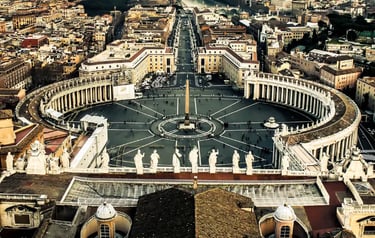Aerial view of St. Peter's Square and the Vatican City cityscape featuring the iconic Egyptian obelisk.