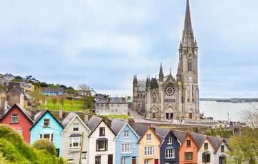 The colorful Deck of Cards houses in Cobh, Ireland, with St. Colman's Cathedral and the harbor in the background.