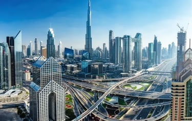 Panoramic view of the Dubai skyline featuring the Burj Khalifa and complex highway interchanges.