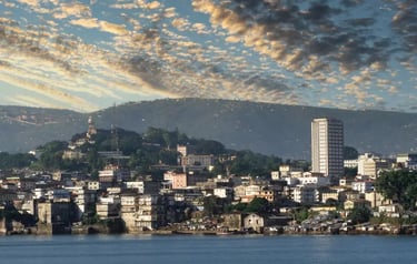 Panoramic view of the Freetown Sierra Leone skyline along the coast under a dramatic sunset sky.