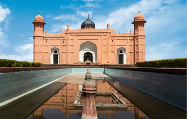 Mausoleum of Bibi Pari at Lalbagh Fort in Dhaka with a reflective pool under a blue sky.