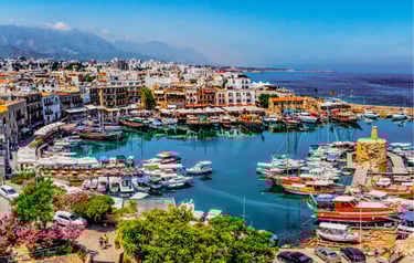 Aerial view of historic Kyrenia Harbour in Cyprus with fishing boats and yachts docked by the Mediterranean Sea.