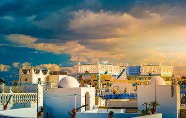 White domed houses in Sidi Bou Said, Tunisia under a dramatic sunset sky with golden clouds.