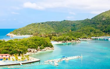 Aerial view of Labadee, Haiti, featuring turquoise Caribbean waters, lush green hills, and a private beach resort dock.