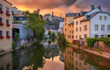 Historic buildings in Luxembourg City's Grund district reflected in the Alzette River at sunset.