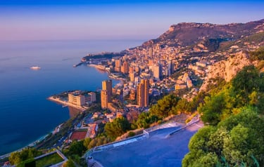 Panoramic sunset view of Monte Carlo, Monaco buildings and coastline from the French Riviera mountains.