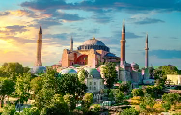 The Hagia Sophia Grand Mosque in Istanbul, Turkey, at sunset with its iconic domes and four minarets.