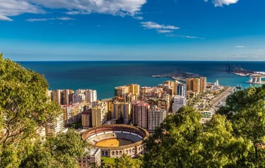 Panoramic aerial view of Malaga city skyline, La Malagueta bullring, and the Mediterranean Sea coast in Spain.