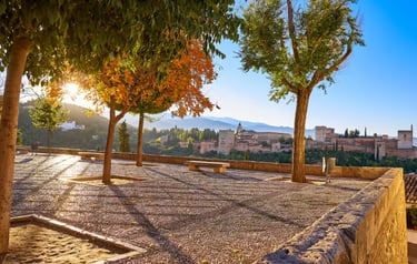 Panoramic view of the Alhambra palace in Granada, Spain at sunset from a cobblestone terrace.