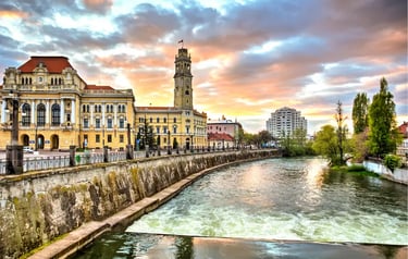 Oradea City Hall and the Crișul Repede river at sunset with colorful clouds over the Romanian architecture.