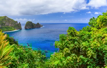 Panoramic view of tropical green cliffs and vibrant blue ocean waters in American Samoa.
