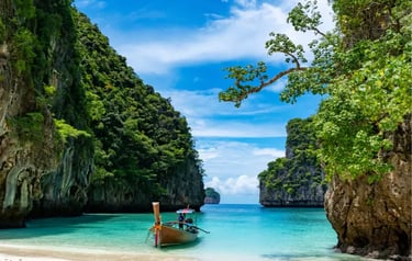 A traditional Thai longtail boat floats on turquoise water at a tropical beach surrounded by limestone cliffs.