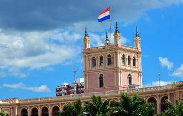 The pink Palacio de los López in Asunción with the Paraguay flag waving under a blue sky.