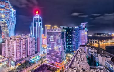 Night view of the Macau skyline featuring illuminated skyscrapers and the Grand Lisboa hotel.