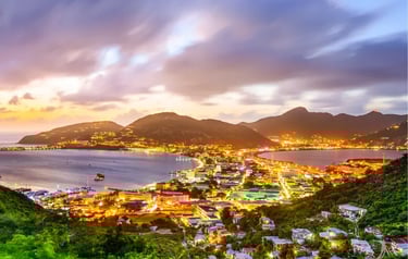 Panoramic night view of Philipsburg, St. Maarten, showing city lights along Great Bay harbor at sunset.