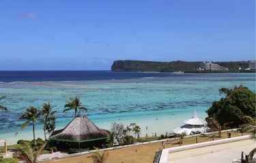 Aerial view of Tumon Bay, Guam beach with turquoise water, palm trees, and Two Lovers Point.