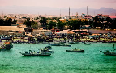 Traditional wooden fishing boats floating in the turquoise harbor of Berbera, Somaliland, near the coastal city.