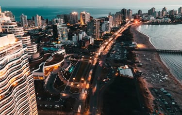 Aerial view of Punta del Este skyline and coastline at sunset with illuminated city lights and beach.