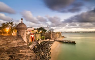 A stone sentry box at Castillo San Felipe del Morro overlooks the Old San Juan coast at dusk.