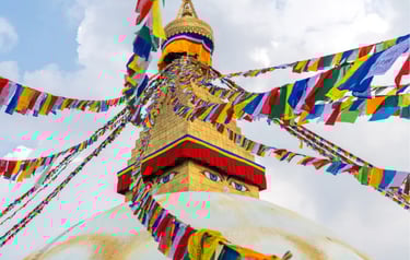 Boudhanath Stupa in Kathmandu Nepal with colorful Tibetan prayer flags under a cloudy sky.