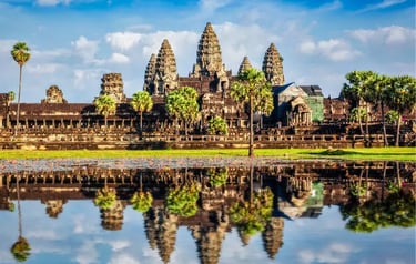 Angkor Wat temple complex in Cambodia reflecting in a lotus pond under a blue sky.