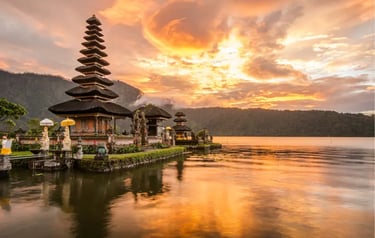 Sunset view of Ulun Danu Beratan Temple on a lake in Bali, Indonesia with mountains.