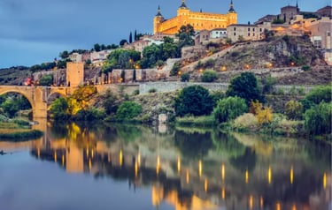 Panoramic sunset view of Alcázar of Toledo fortress reflecting in the Tagus River in Spain.