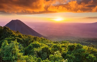 Golden sunset over Izalco Volcano and lush green forest landscape in El Salvador.