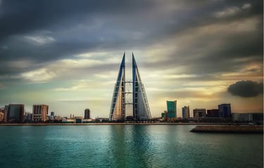 The Bahrain World Trade Center twin towers overlook the Manama skyline and Persian Gulf at sunset.