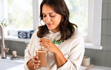 a woman in a white shirt and blue skirt drinking a drink